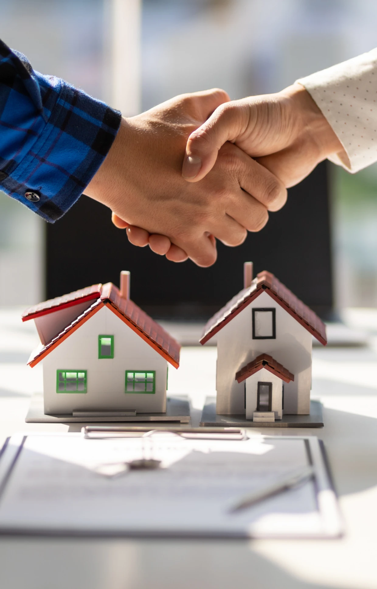 Handshake over miniature houses and documents